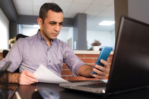 Tired Man In Office Has Difficulty To See Texts On His Smartphone, Concept For The Beginning Of Presbyopia Just After The Age Of 40 Years.